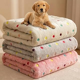 Three fluffy flannel dog blankets in cream, grey and pink with colourful dot print, stacked with a puppy on top